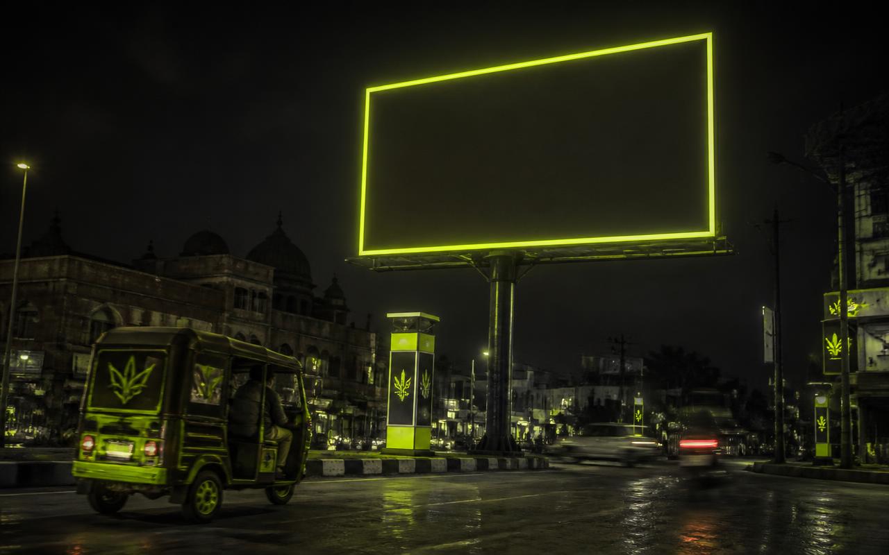 Night-time billboard, pole kiosks and branded e-rickshaw on a Punjab street